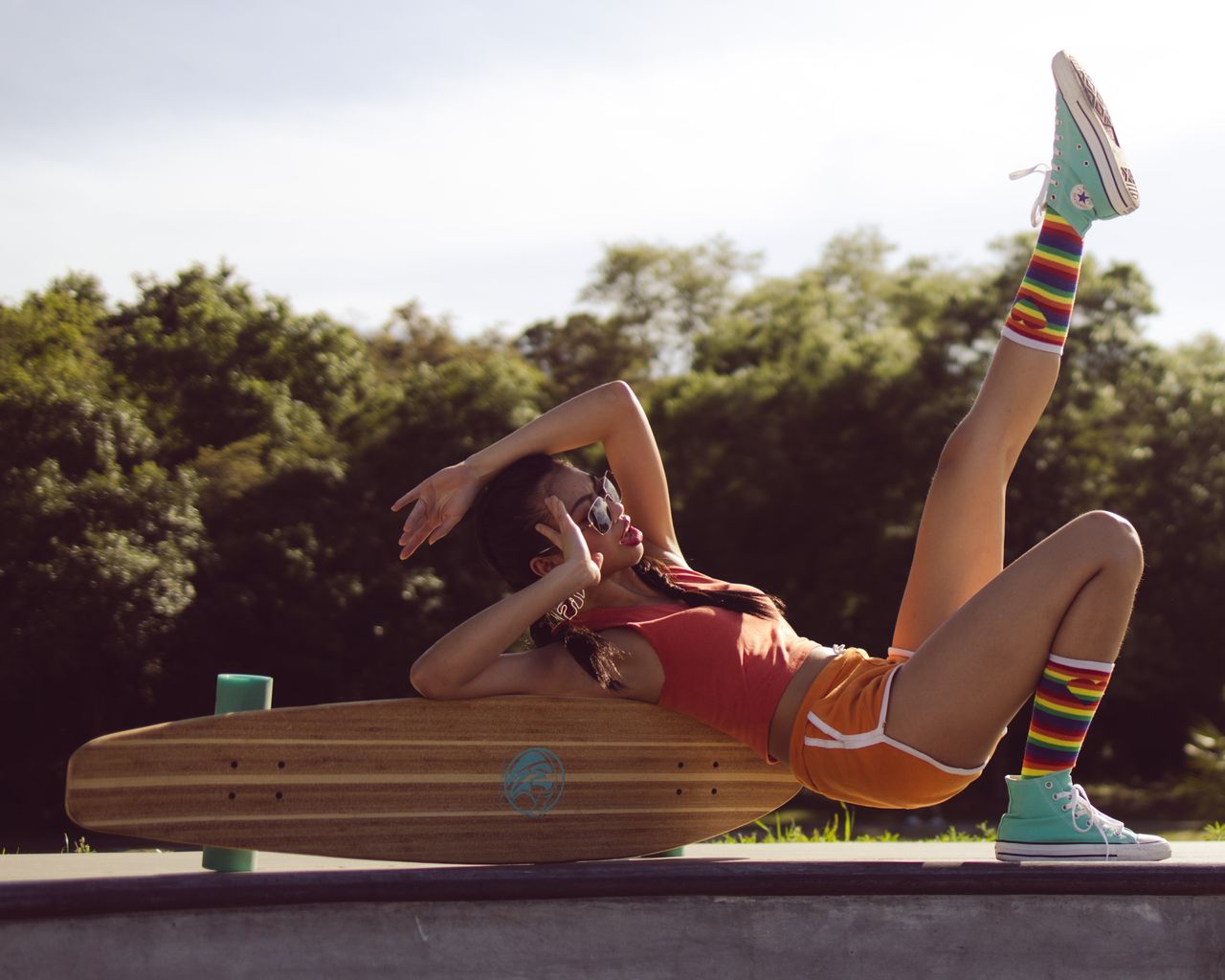 Woman in sportswear reclining on a skateboard outdoors, enjoying leisure time under the sun.