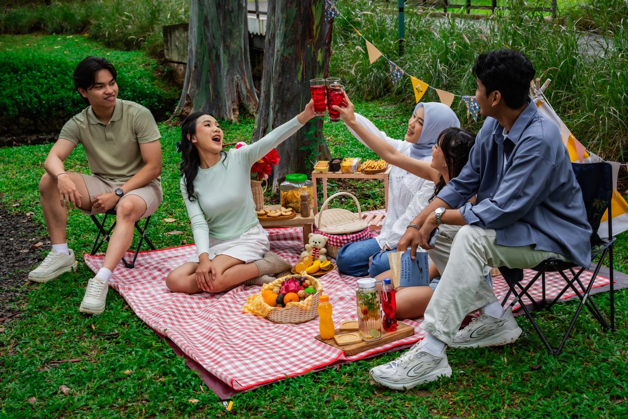our-experience A cheerful group of friends enjoying a vibrant picnic in a lush garden setting in Indonesia.