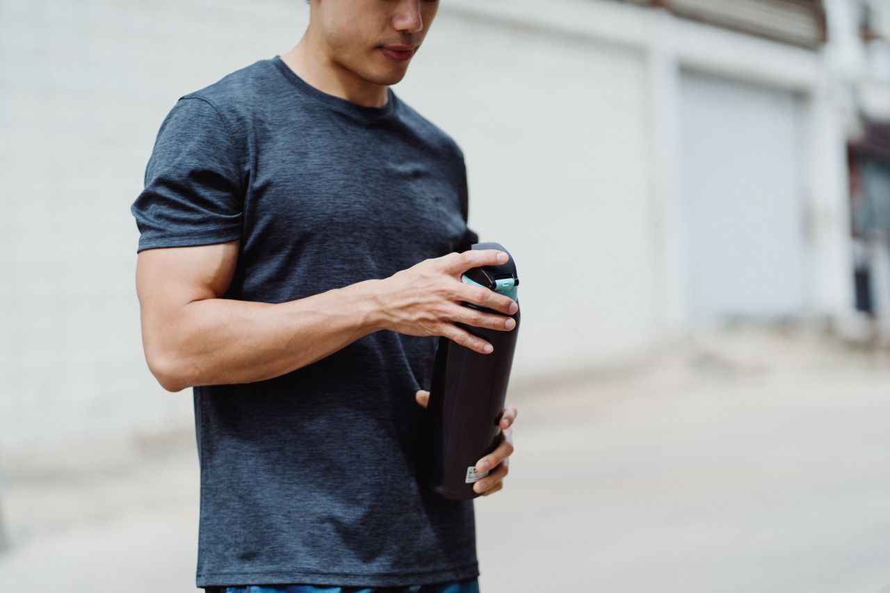 about-img Young man holding a water bottle during his street workout session outdoors.